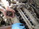 2003 Ford Taurus - Hands are shown holding walnut shells over a car's engine intake manifold, possibly for cleaning purposes.