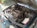 2003 Ford Taurus - The engine bay of a green 2003 Ford Taurus is shown with the hood open, revealing the engine and surrounding components.