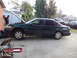 2003 Ford Taurus - Mechanic works on a green sedan parked in a driveway with the hood up.