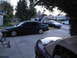 2003 Ford Taurus - A dark green sedan with its trunk open is parked on a concrete driveway, alongside other vehicles.