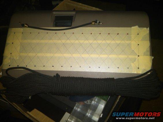 Gray car part with taped grid and rope, likely for installation