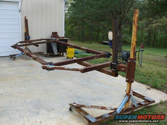 Homemade metal frame jig with wheels, designed to hold a car body