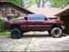 2001 Dodge 1500 - Maroon 2001 Dodge 1500 pickup truck, lifted with large off-road tires, parked on a concrete driveway.