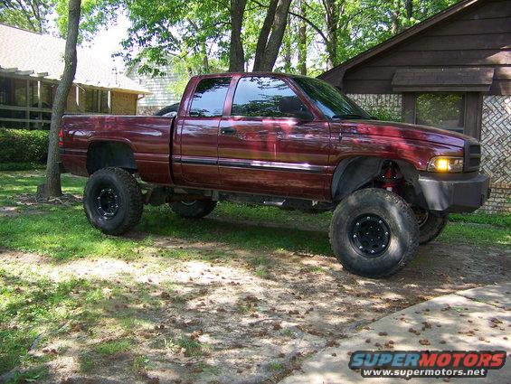 Maroon 2001 Dodge 1500 pickup truck with lifted suspension and large off-road tires