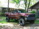 2001 Dodge 1500 - This lifted 2001 Dodge 1500 pickup truck is parked in a residential setting with trees and houses in the background.