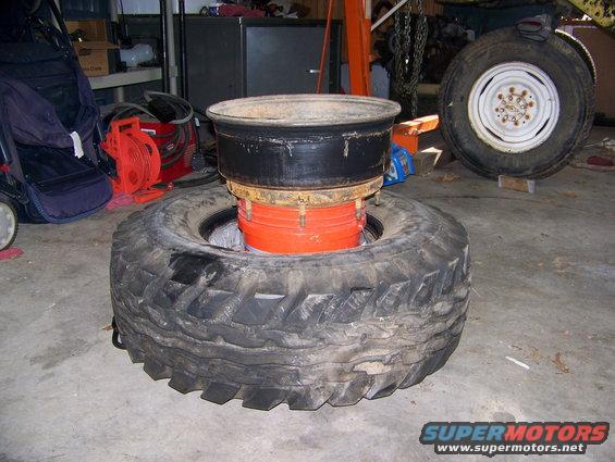 Tire with a rim and orange bucket inside, another wheel in background