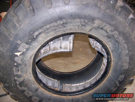 Damaged tire beadlock with 'Wrangler' and 'Goodyear' visible