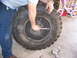 2001 Dodge 1500 - A person works on a large tire, with a child's bicycle visible in the background.