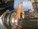 2001 Dodge 1500 - A worker welds a large metal wheel rim in a dimly lit industrial setting.