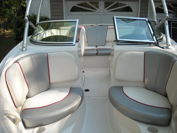 Boat interior with white and gray seats, red trim, and windshields