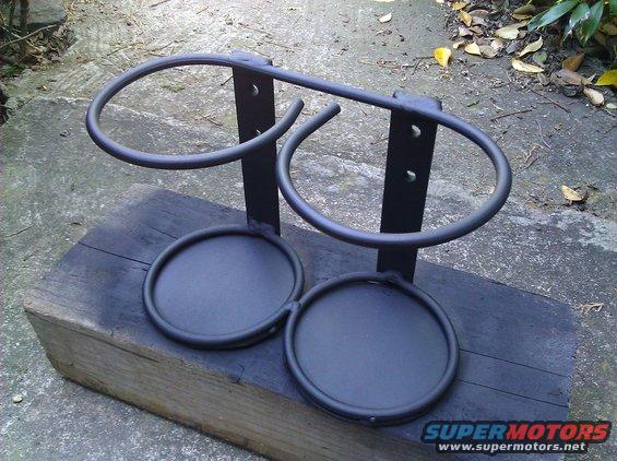 Black metal dual cup holder assembly with two large rings and two smaller circular bases, mounted on a wooden block