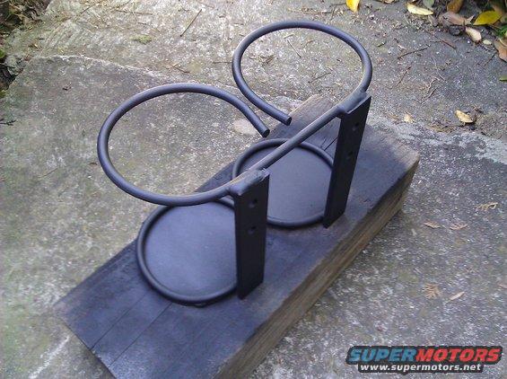 Custom dual cup holder assembly, painted black, mounted on a wooden block
