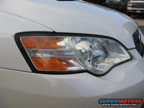 Close-up of a white car's front headlight assembly with orange turn signal