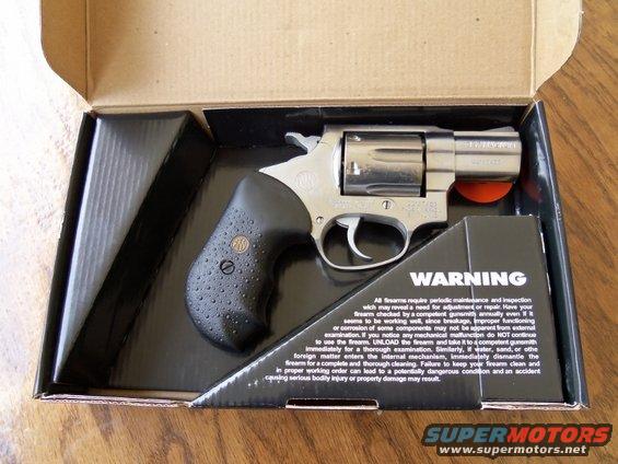 Revolver handgun in its box with a warning label