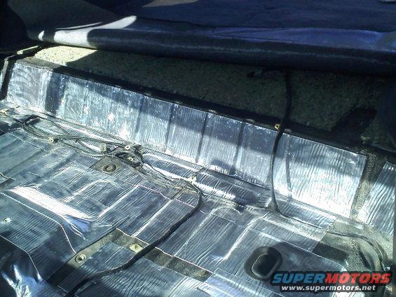 Interior floor of a vehicle with sound deadening material applied. Wires are visible