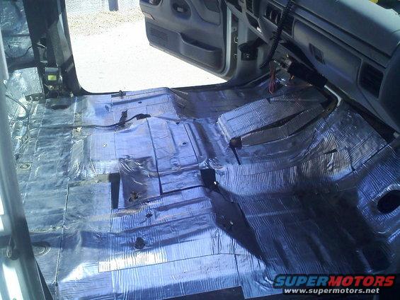 Vehicle interior with sound deadening material covering the floor and lower door panels