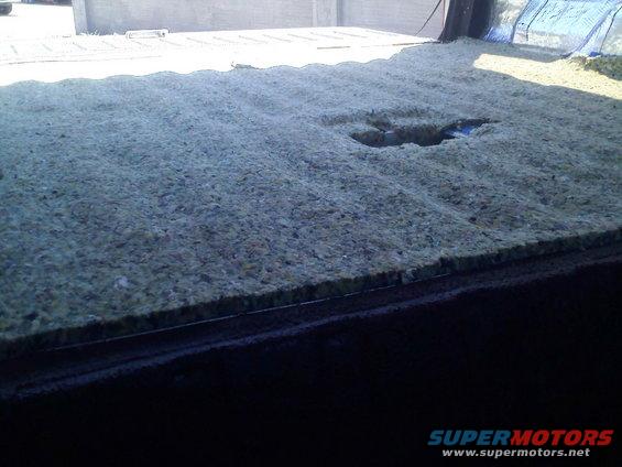Insulation material covering the floor of a vehicle's cargo area, with a hole in the center