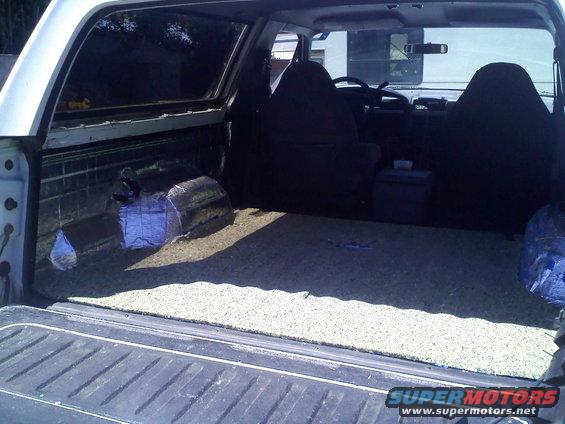 White SUV interior cargo area with sound deadening material on wheel wells and carpeted floor