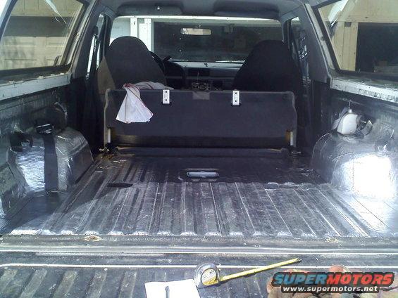 View of the empty truck bed and the back of the cabin, showing seats and a partition
