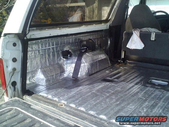 Interior of white SUV cargo area with sound deadening material and seat visible