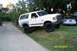 1989 Ford Bronco - A white Ford Bronco with aftermarket modifications is parked on a grassy area next to a concrete driveway.