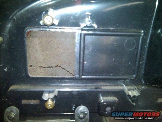 Close-up of a cracked panel with two rectangular openings on a black dashboard