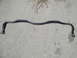 2003 Ford Taurus - A black sway bar lies on a concrete surface, likely a replacement part for a vehicle.