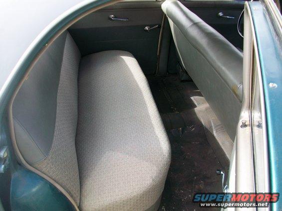 Back seat and floor of an old car. Door is open on the right