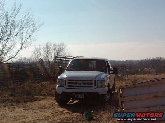 Front view of a white 2003 Ford F-250 pickup truck parked in a dry, rural area