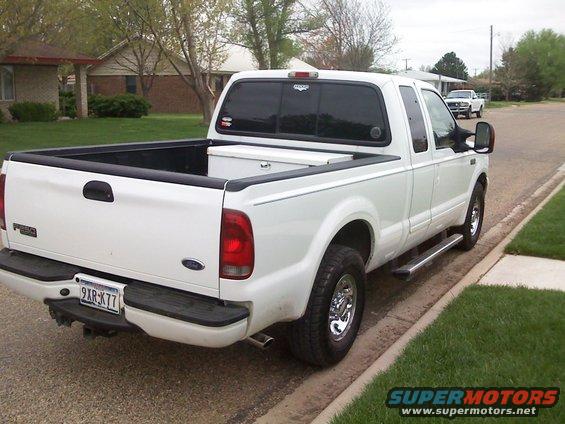 White 2003 Ford F-250 pickup truck, rear 3/4 view, parked on a residential street