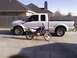2003 Ford F-250 - A white 2003 Ford F-250 pickup truck is parked next to a blue dirt bike.