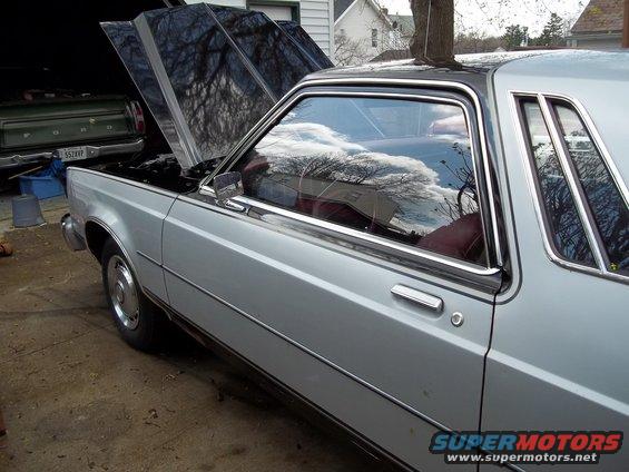 Silver sedan with hood open, parked next to a green Ford pickup truck