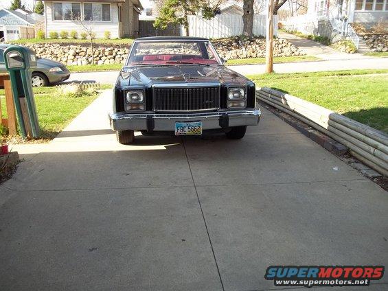 Front view of a dark colored Ford Fairmont Futura parked in a driveway. Red interior visible