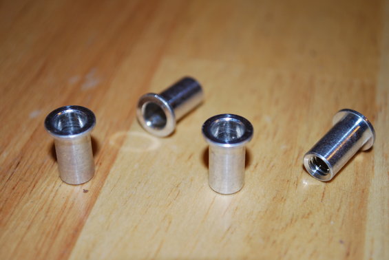 Four silver rivet nuts on a wooden surface