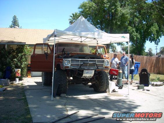 Lifted 1970 Ford F-Series truck with hood open, parked under a canopy. License plate reads LNPE213