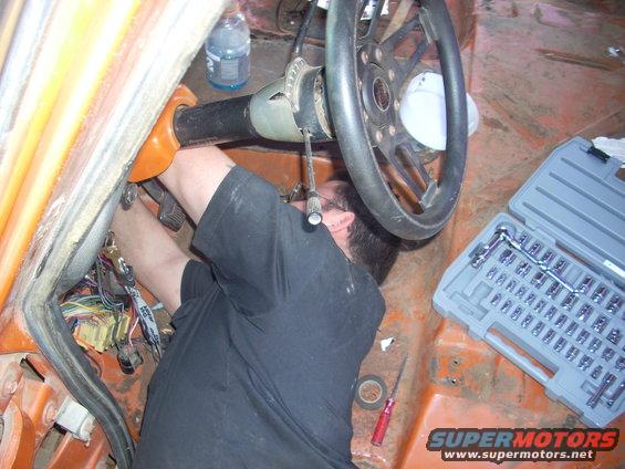 Interior view of a person working on the steering column with a socket set nearby