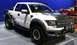 2011 Ford F-150 - White 2011 Ford F-150 Raptor SVT truck with "FORD RACING" banner and aftermarket lights.