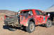 2011 Ford F-150 - A red off-road truck, possibly a Ford F-150 Raptor, is seen from the rear with a spare tire mounted and racing decals on its side.