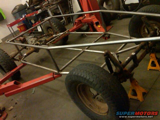 Custom tube chassis buggy project with suspension components and tires on jack stands