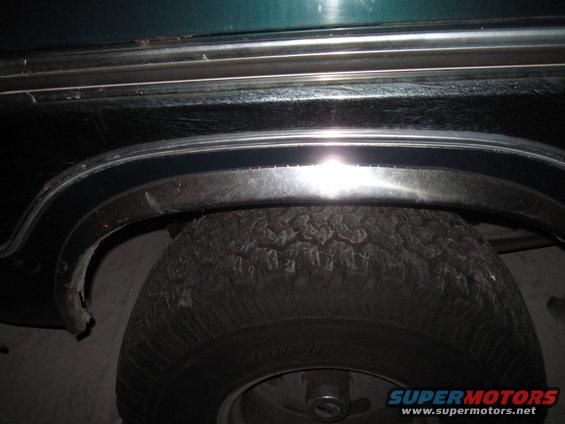 Green 1979 Ford Bronco rear wheel well with chrome trim and tire
