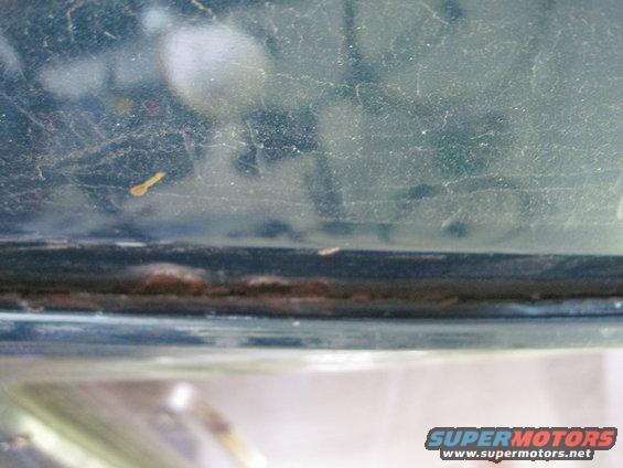 Close-up of a dusty, possibly rusted window frame on a dark green vehicle