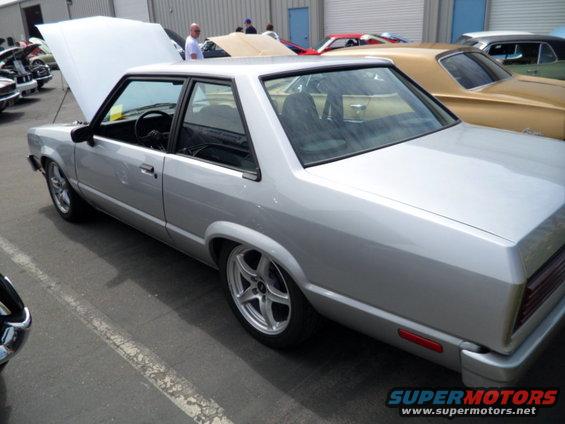 Silver coupe with hood up, parked next to a gold car
