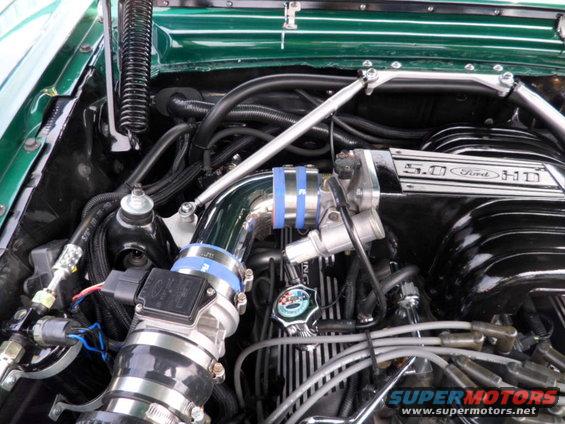 Green car engine bay with chrome intake and "5.0 Ford HD" valve cover
