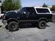 1991 Ford Bronco - This black Ford Bronco features a white removable top and is lifted with off-road tires.