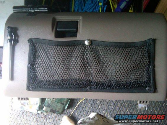 Brown interior door panel with a black mesh pocket and a flashlight attached