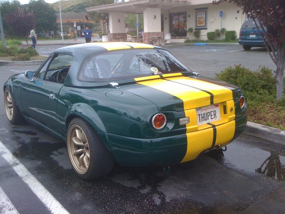 Rear view of a green convertible with yellow stripes and a 'THUPER' license plate