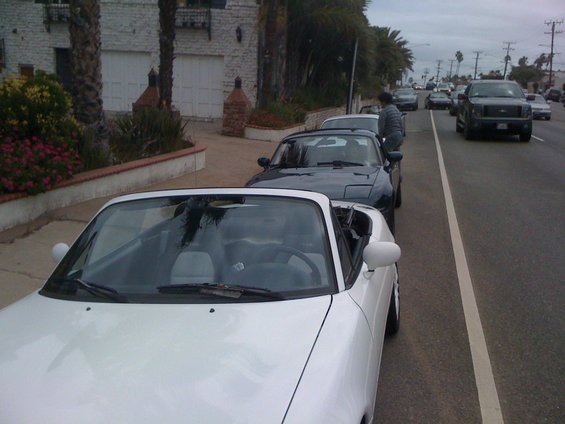 White 1991 Mazda Miata parked on street, another Miata behind it