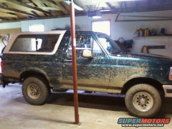 Mud-covered green Ford Bronco parked inside a garage