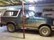 1993 Ford Bronco - This green Ford Bronco is covered in mud and parked indoors.