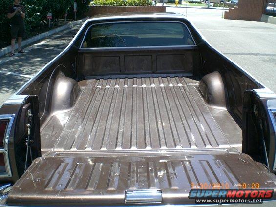 Brown 1979 Ford Ranchero pickup truck bed with tailgate down, chrome bumper, and visible watermarks